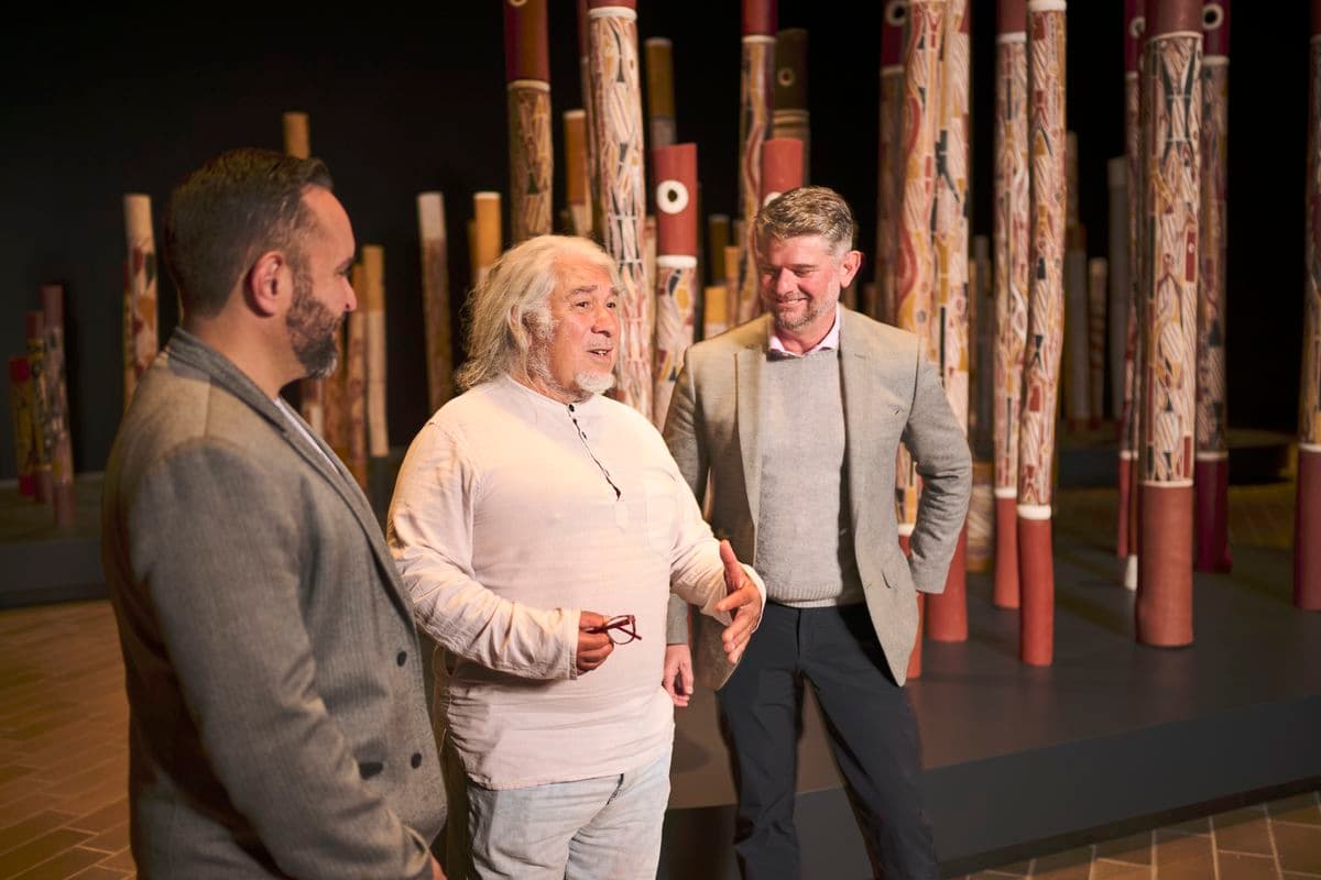 Three men standing among a Bruce, Djon and Nick hollow log coffins from central Arnhem Land