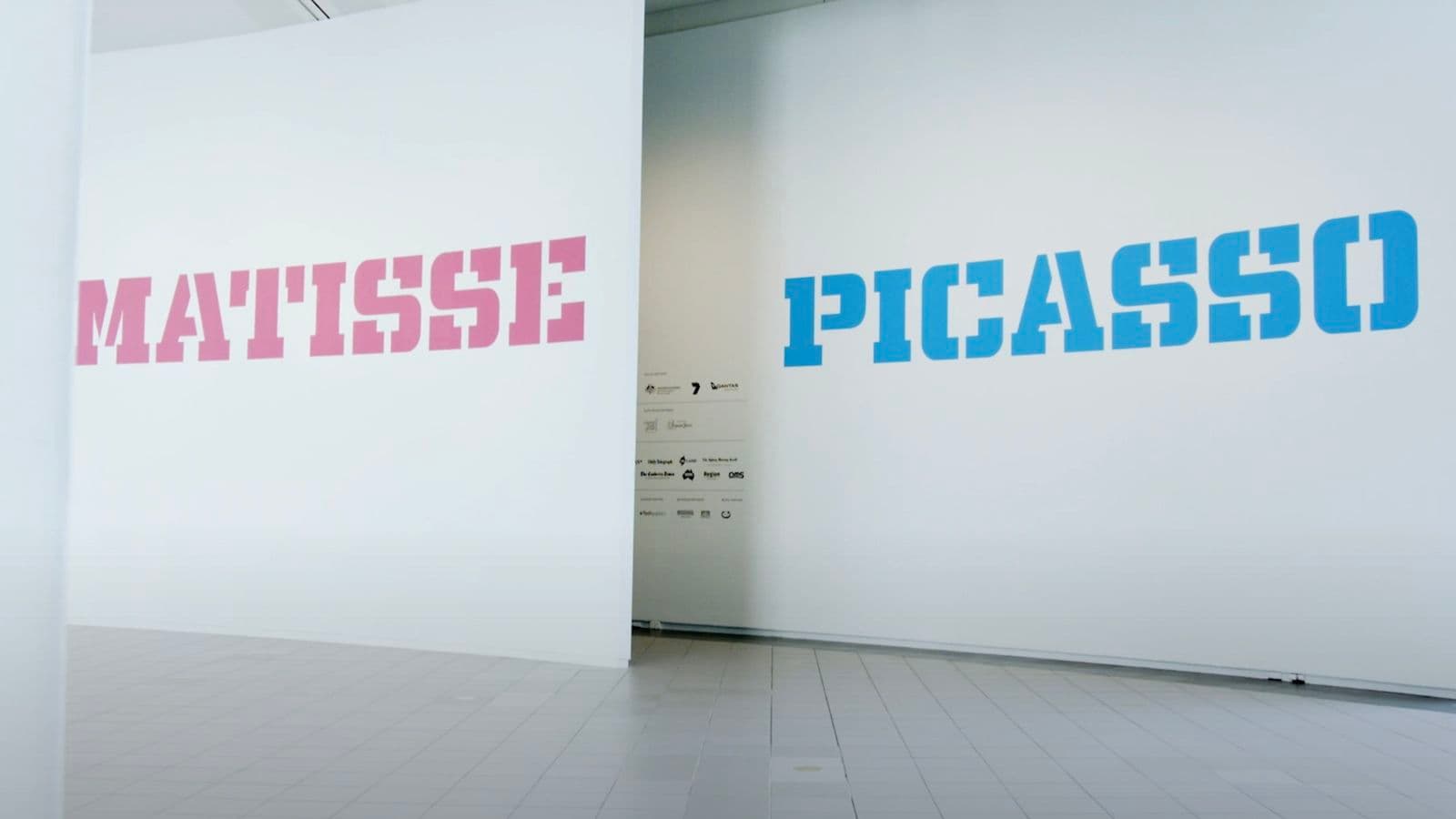 Video still of exhibition entrance with wall text that reads “Matisse, Picasso”.