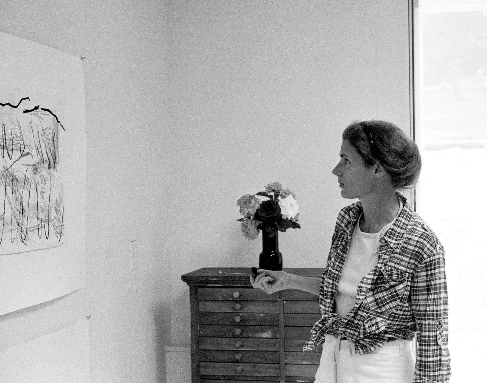 A woman in a room looking at artwork on a wall