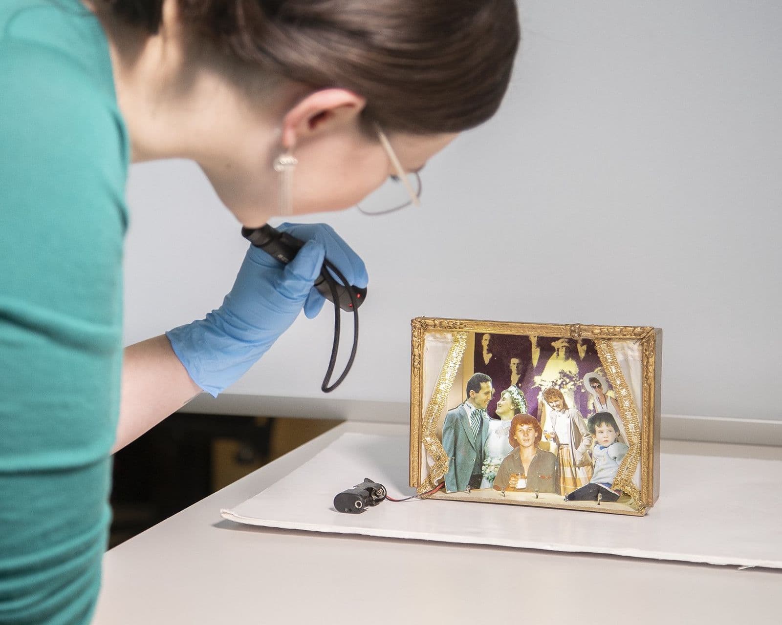 Photograph of conservator checking small object with light