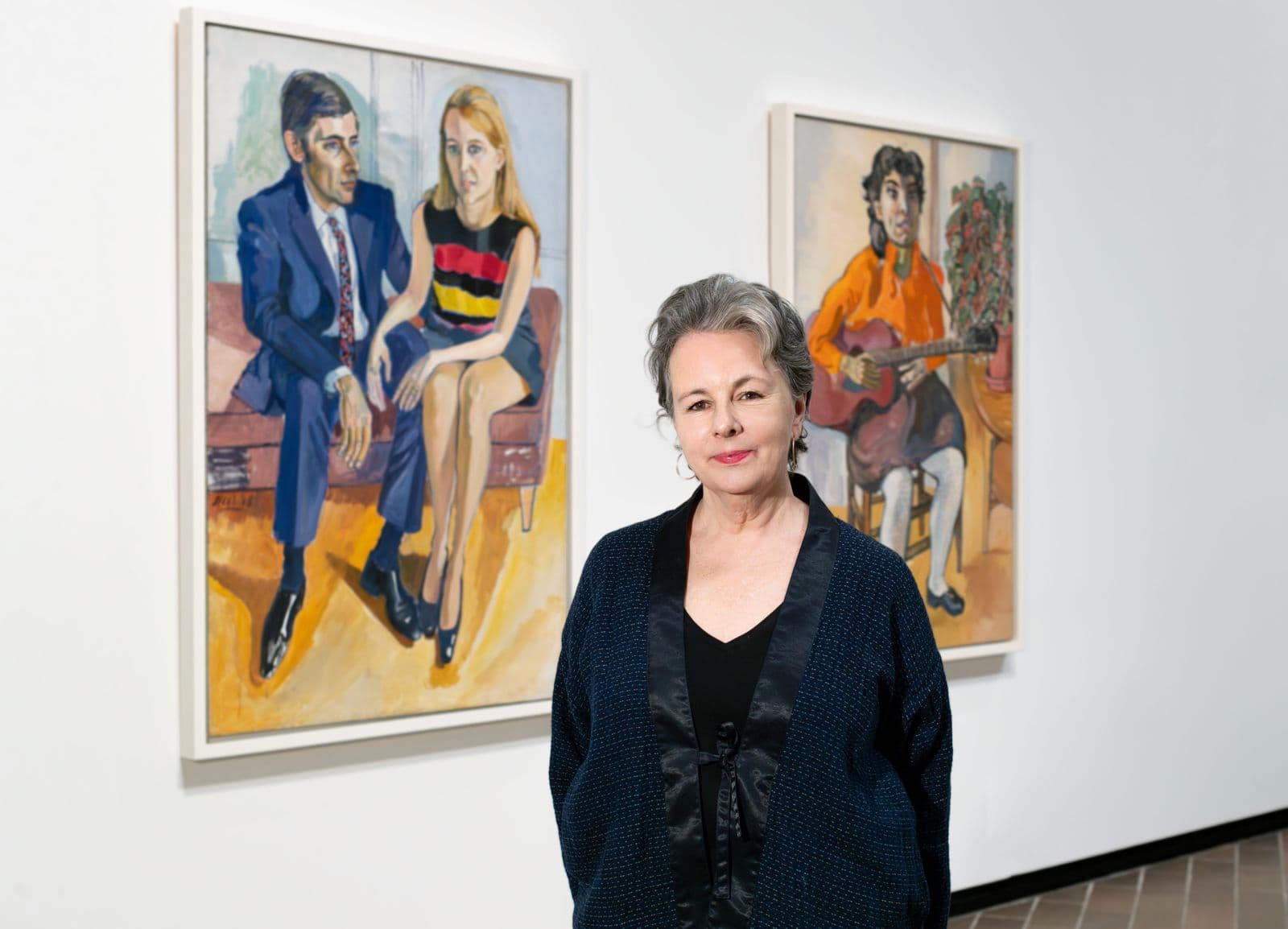 A picture of a woman in front of two works of art.