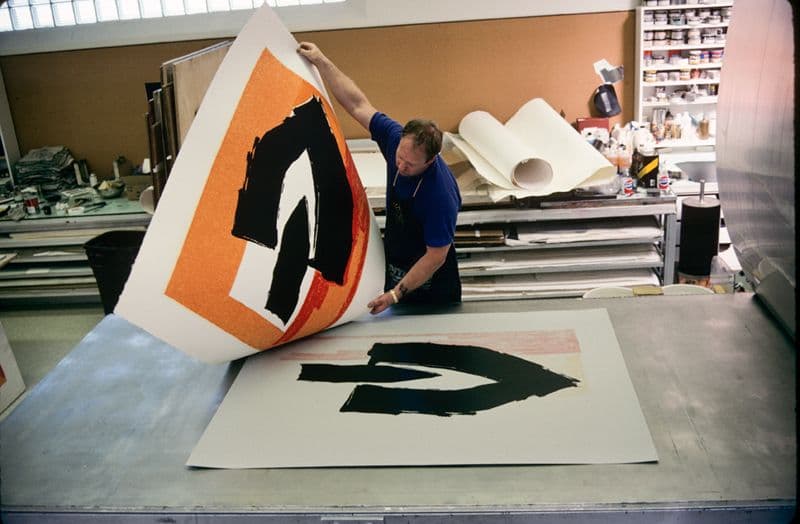 Colour photograph of John Hutcheson lifting Robert Motherwell’s ‘Black cathedral’ from offset lithography press