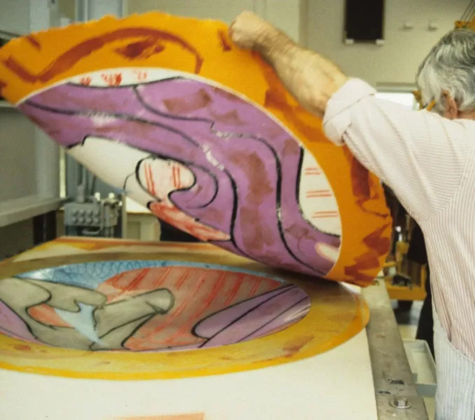 Colour photo of Kenneth Tyler lifting a coloured, experimental impression from a printing element