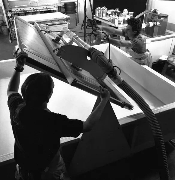 Black and white image of two men using machinery to turn mould upwards