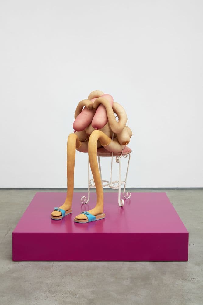 sculpture depicting abstract figure sitting on chair