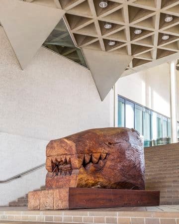 A large wooden sculpture of a crocodile like head on brick steps