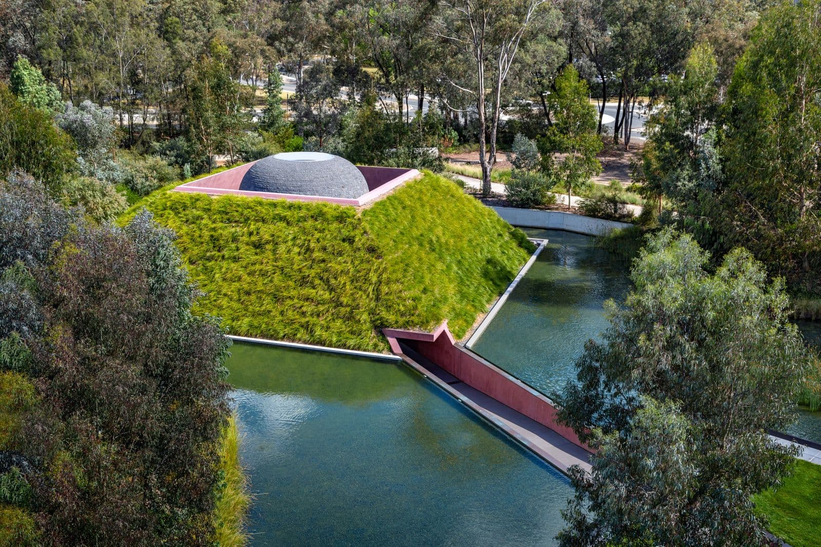 Large sculptural work, pyramid shaped with greenery on the side of the structure.