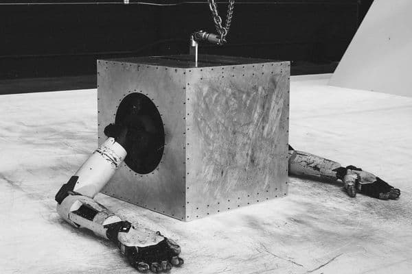 A robot in the shape of a cube sitting on a white floor
