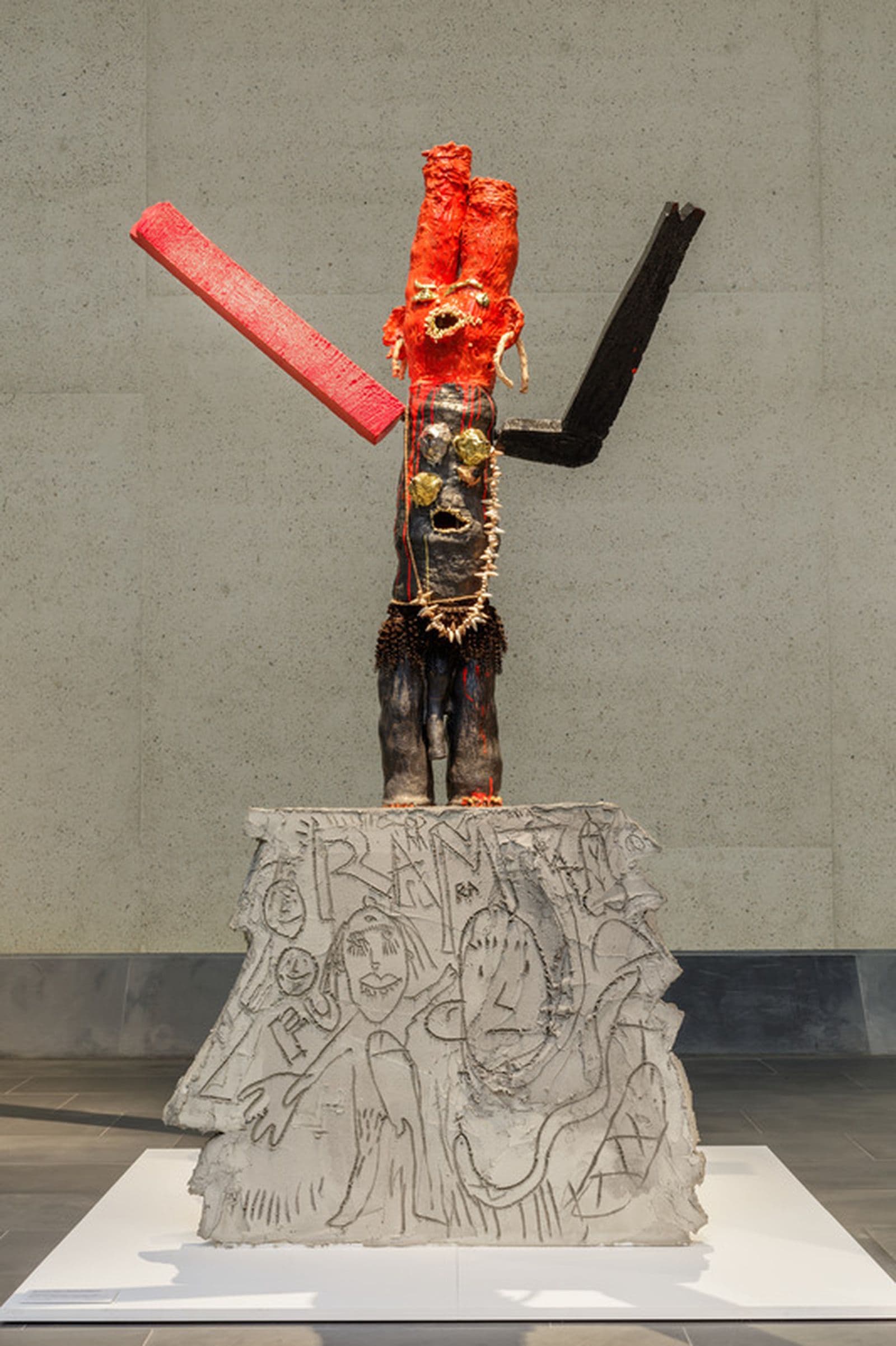 A ceramic sculpture of a vaguely humanoid figure atop a cement platform