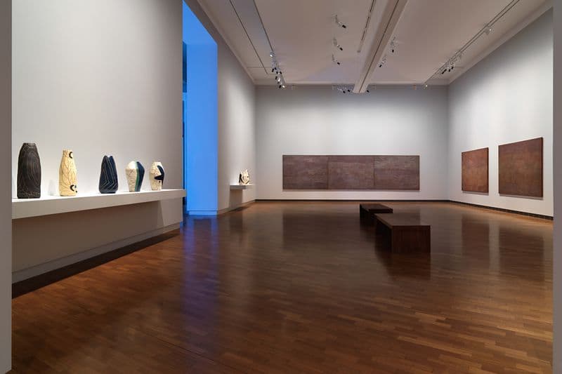 An installation view of vases and paintings within a gallery space