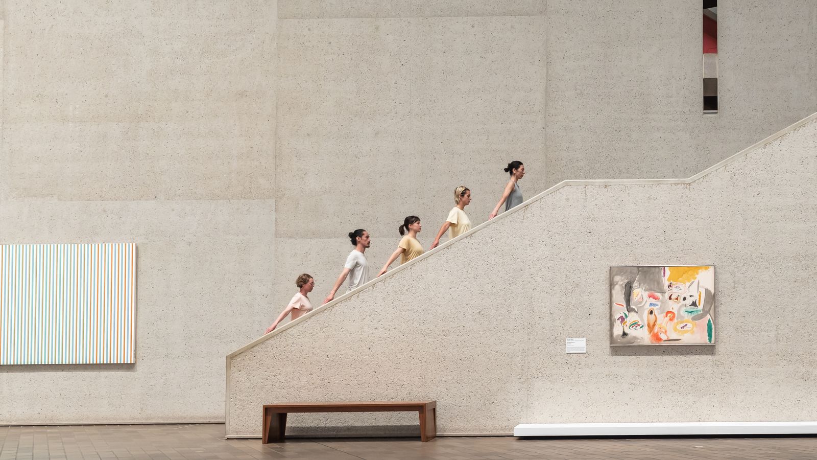 A group of dancers walked up stairs in the brutalist National Gallery architecture.