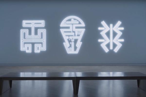 screenshot of a video still showing a neon light artwork installed in a gallery space