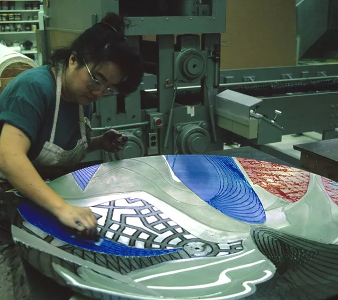 Colour photo of woman applying coloured ink to shaped magnesium element