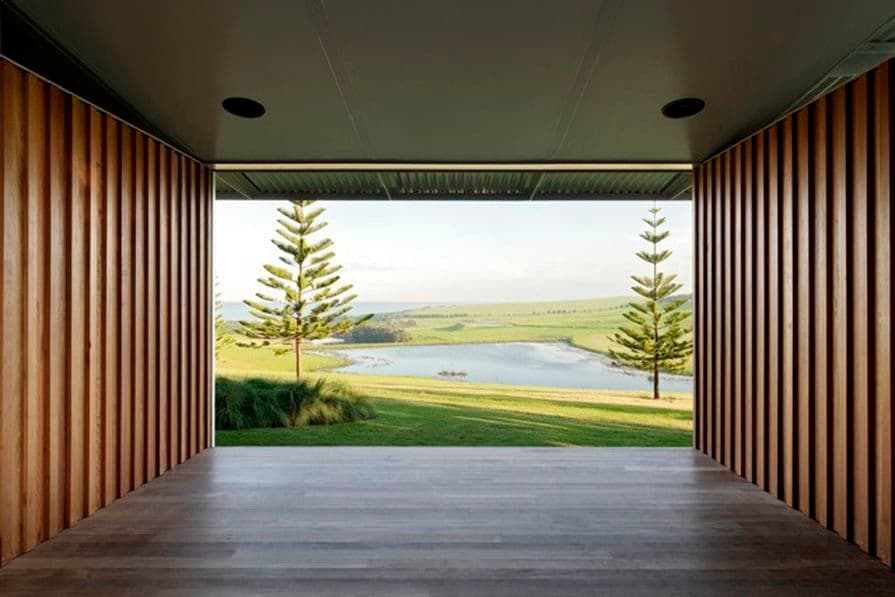 Photograph of interior wooden space with grass in background