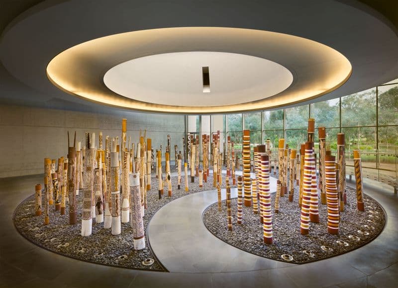 Installation of 200 painted hollow logs placed in a gallery space, with a pathway through the logs