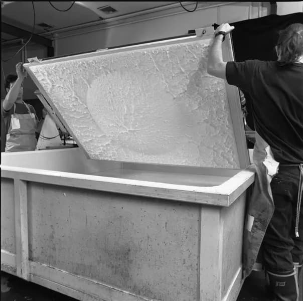 Black and white photo of two men turning white mould upwards