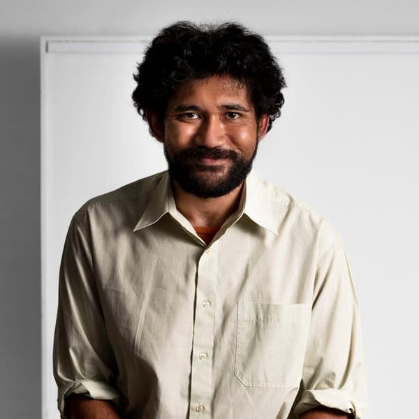 Photographic portrait of a man standing against a white background.