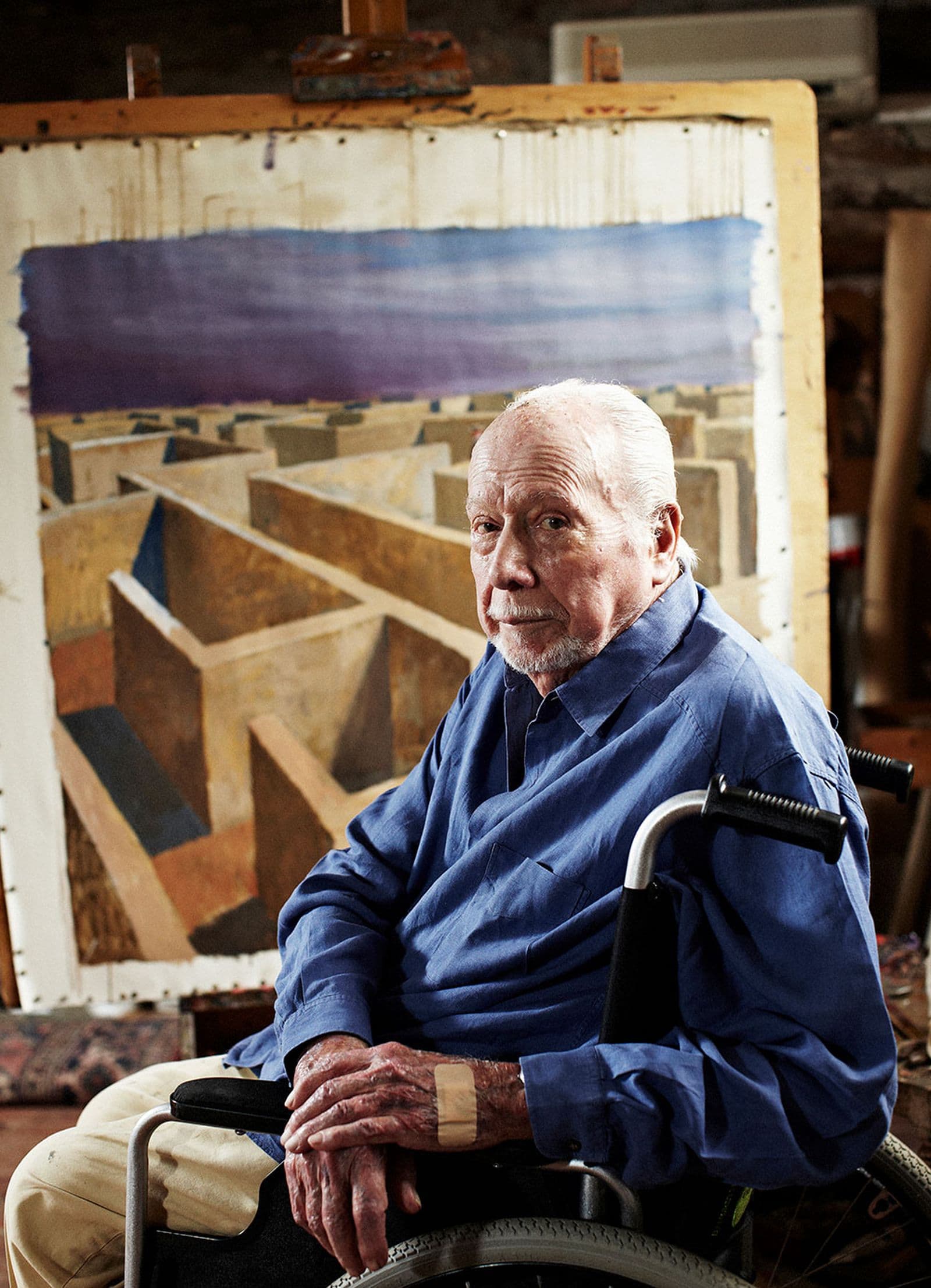 A man seated in a wheelchair in front of a painted canvas