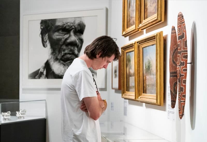 Photograph of visitor looking at caption, with art in background