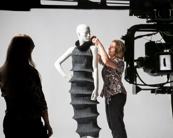 Photograph of black dress on mannequin being photographed behind the scenes