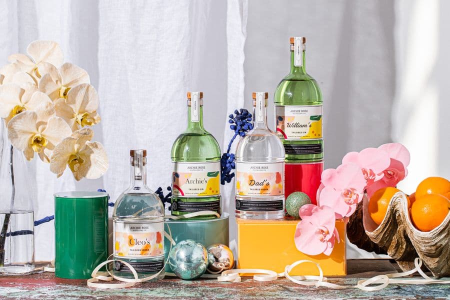 Four bottles of gin are arranged among flowers, baubles and streamers