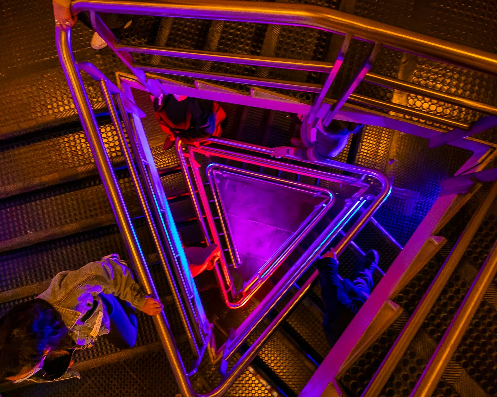 people walking down a triangular staircase