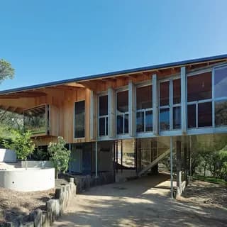 Photograph of domestic building exterior, elevated above garden with windows