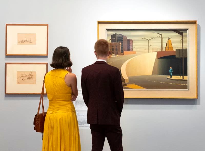 Photo of a woman and a man looking at an artwork on the wall of the Gallery.