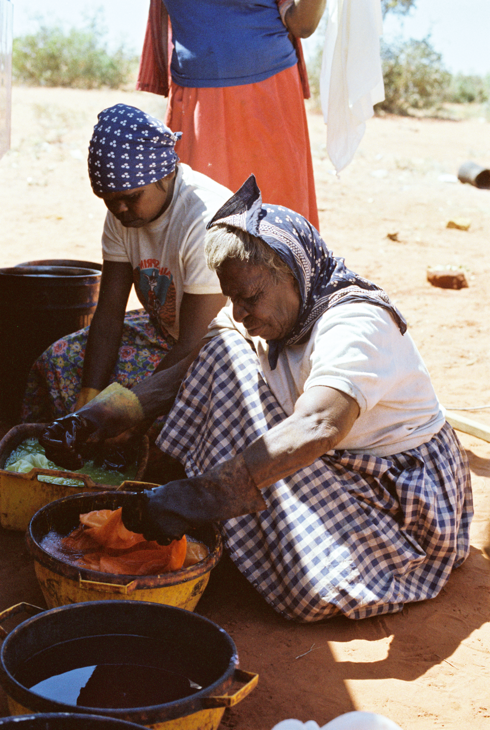 Photograph of two women bent over a pot