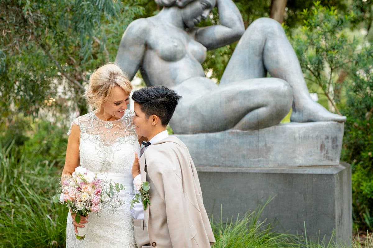 Photograph of couple embracing in front of sculpture of woman in sculpture garden