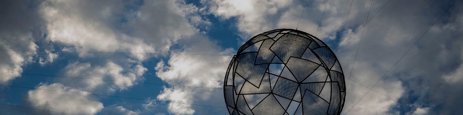 A sphere made of interlocking geometric shapes hangs in the sky