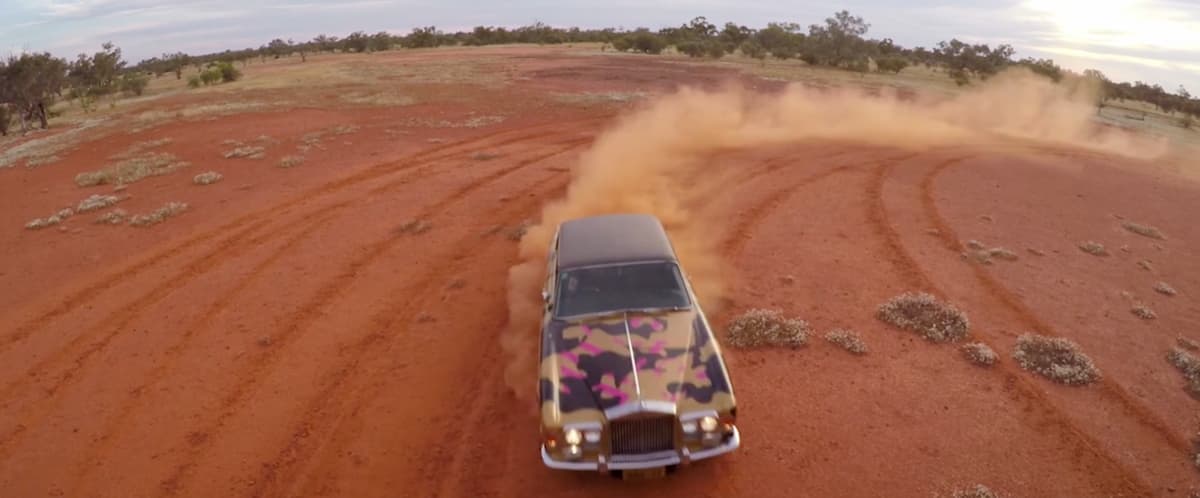 A video still of a car driving through the desert