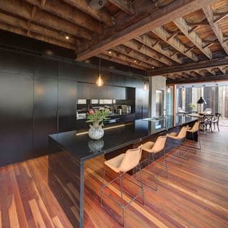 Interior shot of kitchen with black wood cabinets and wooden ceiling