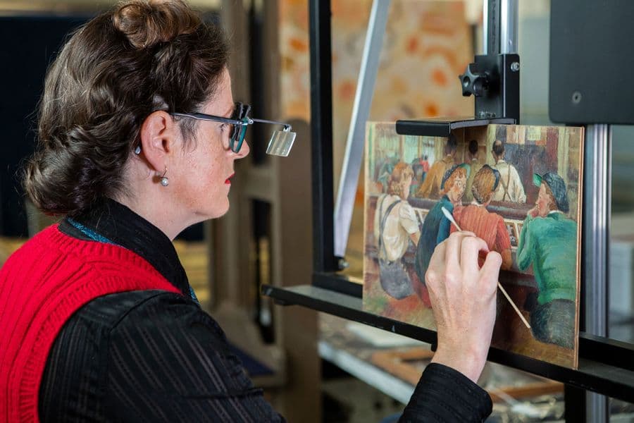Photograph of conservators restoring painting
