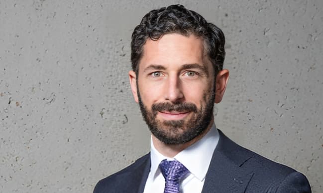Portrait of a brunette man in a navy suit and blue tie