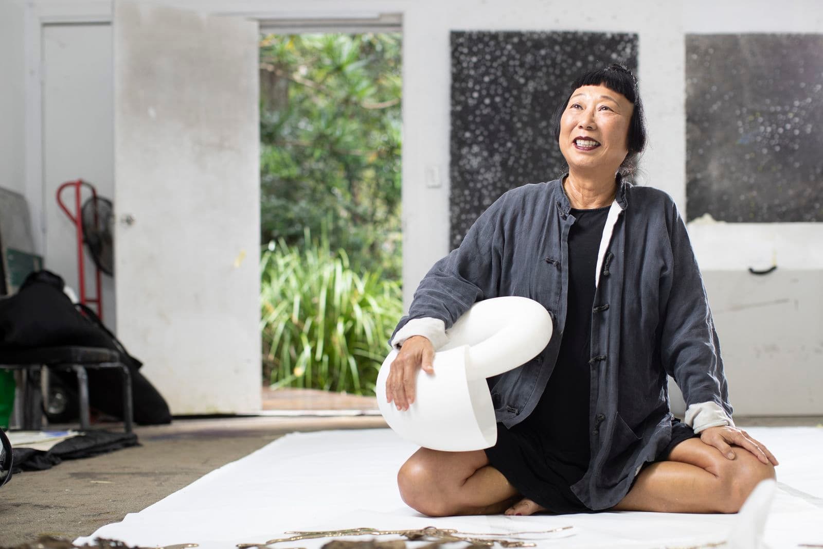 Woman artist sitting on her studio floor holding a sculpture maquette