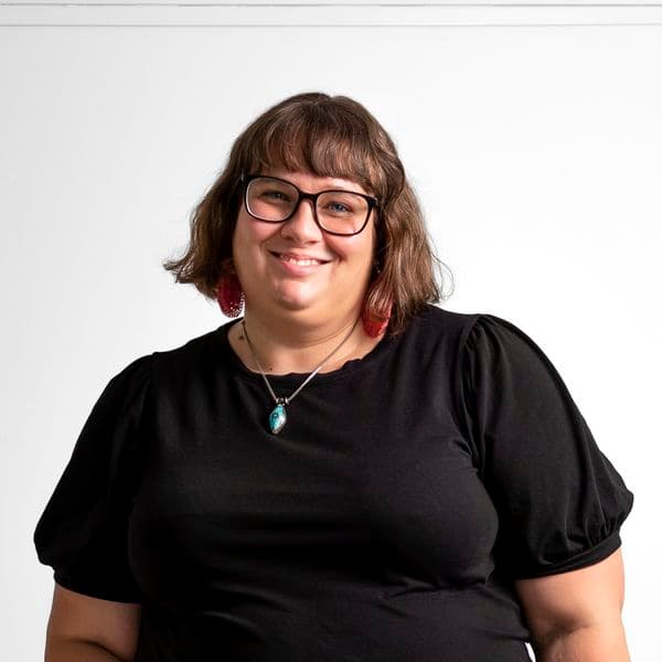 Photographic portrait of a woman standing against a white background.