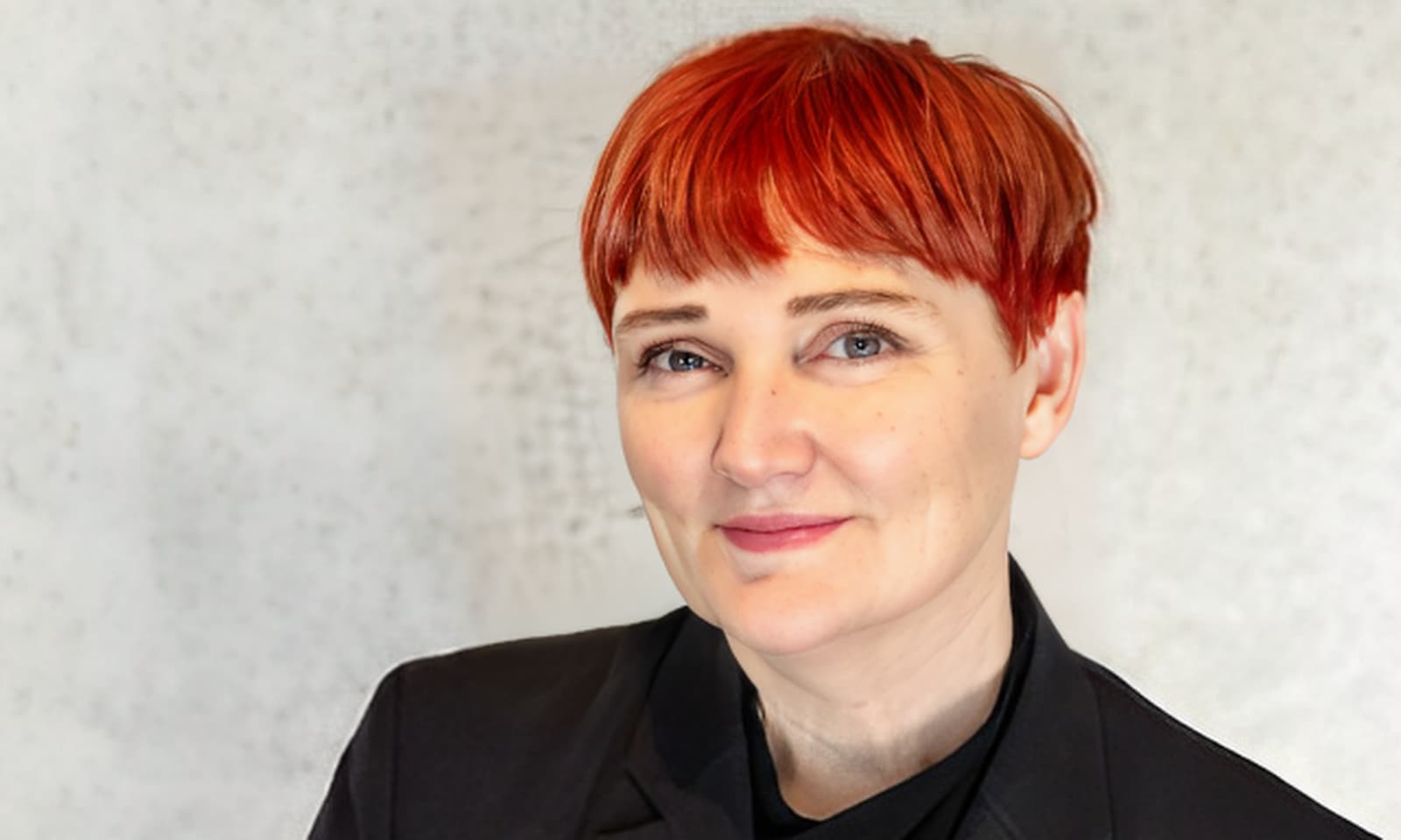 Portrait of a smiling redhead woman in an all black suit