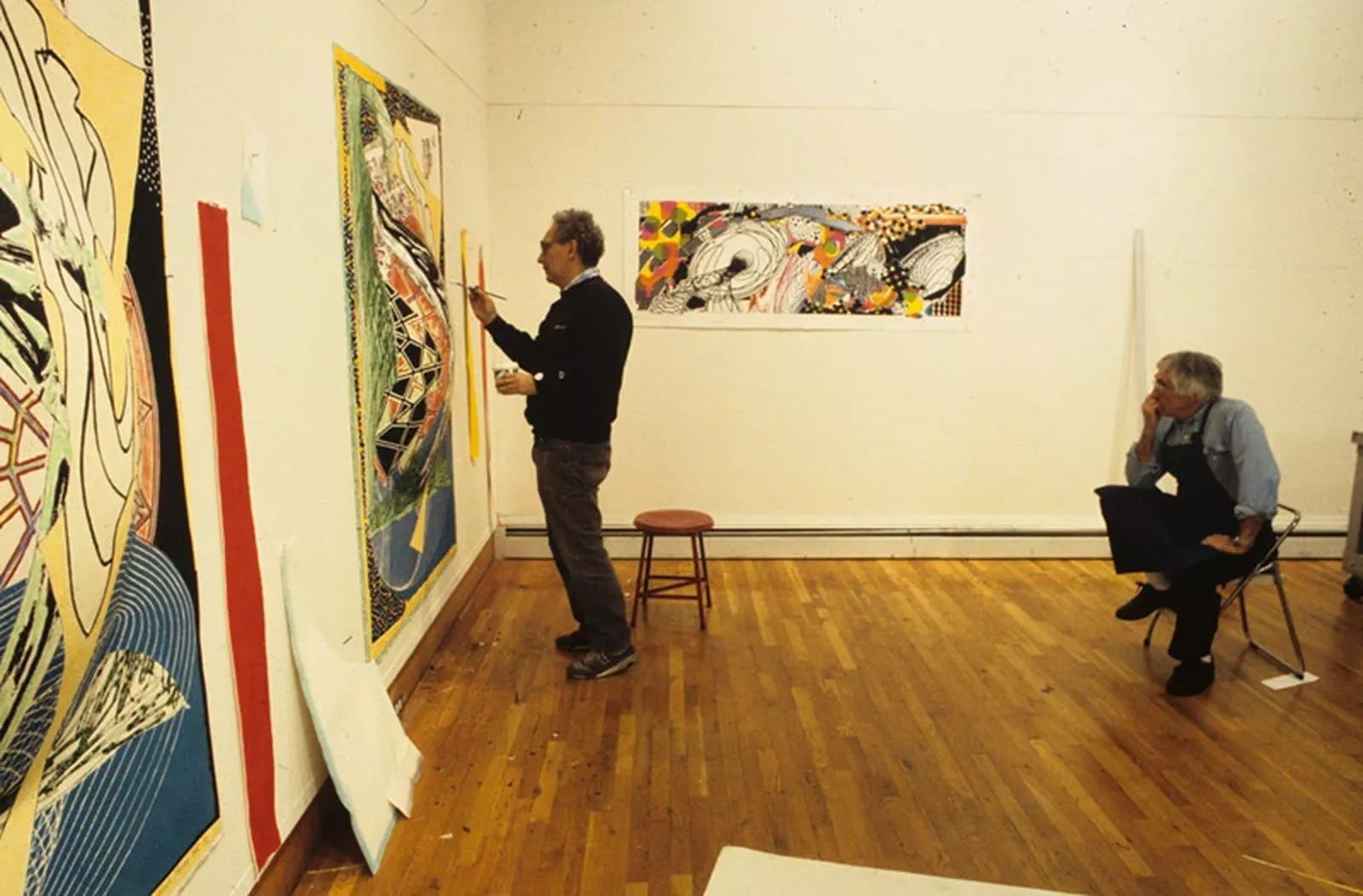 Colour photograph of Kenneth Tyler watching Frank Stella touch up a work from the Moby Dick Domes series