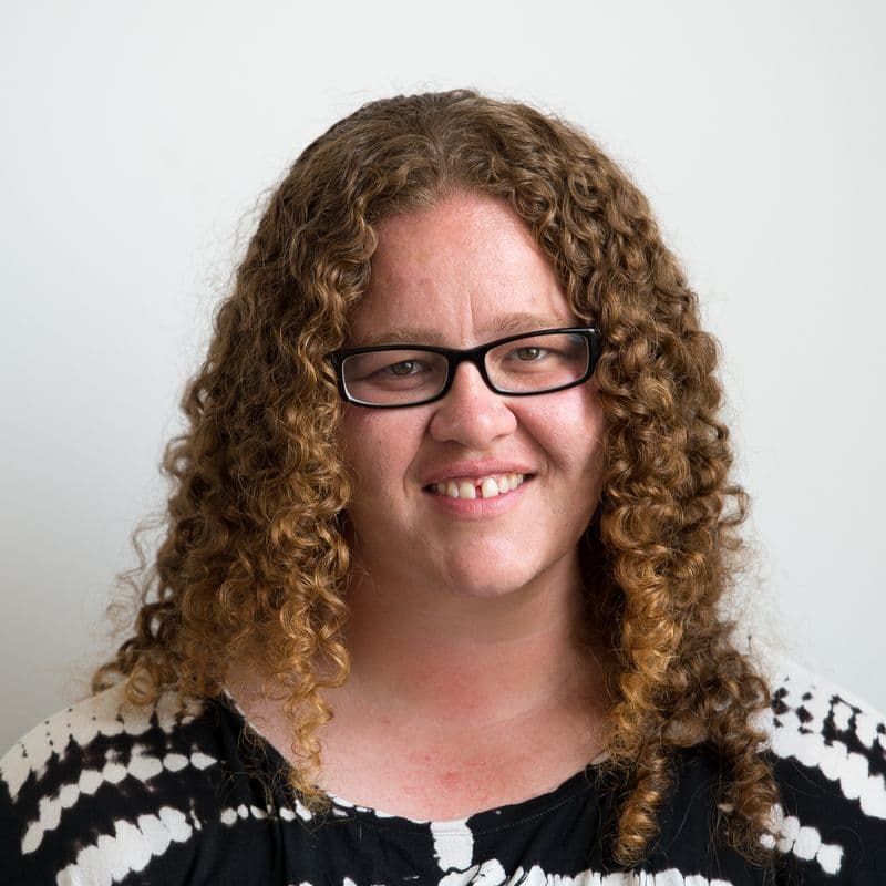 Photographic portrait of a woman standing against a white background.