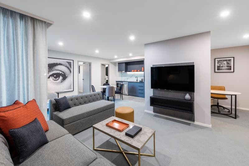 View of hotel room showing a couch, tv and kitchenette