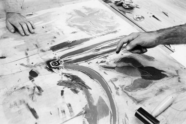 Close up of two male hands gesturing to artwork on a table