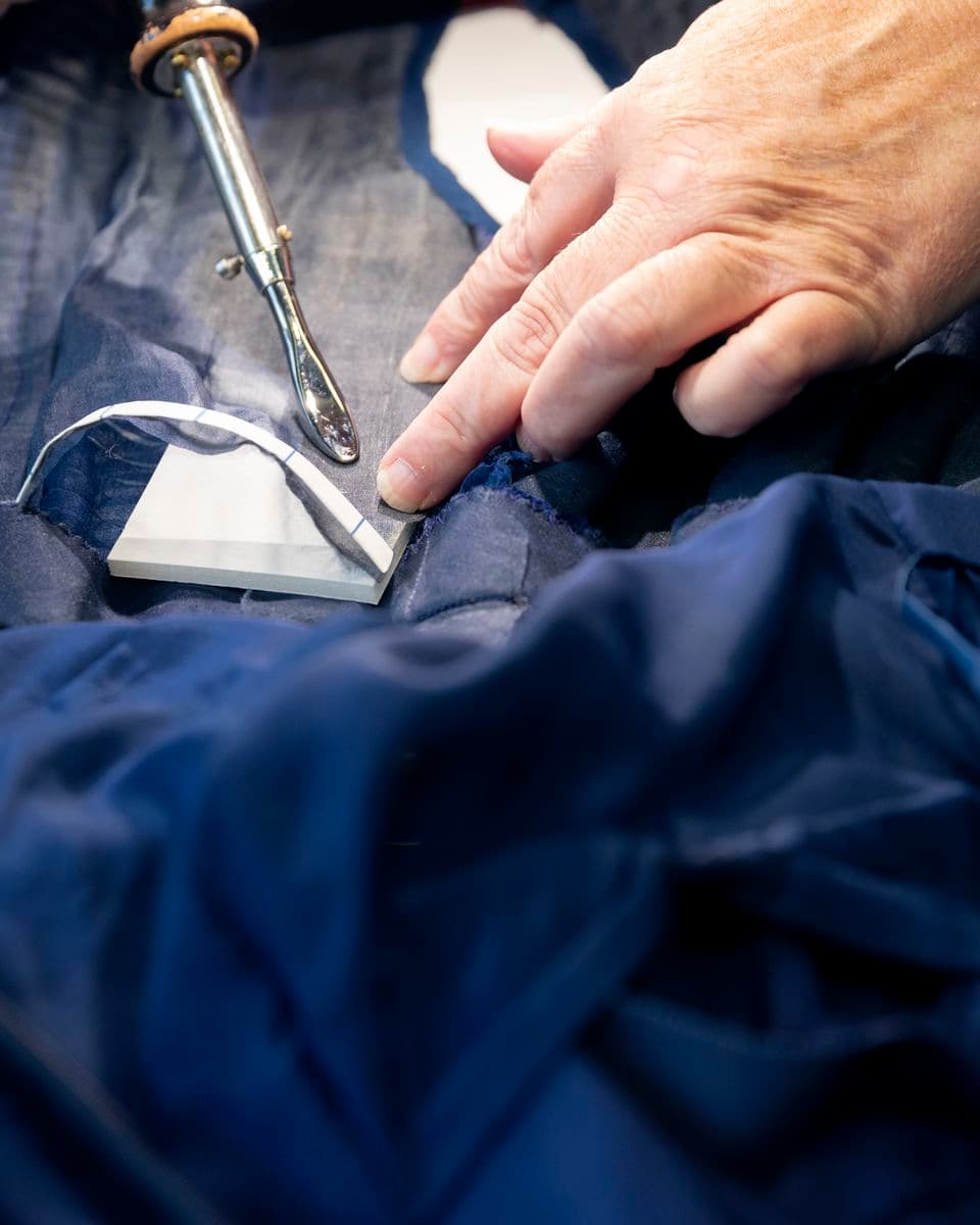 Colour photograph detail of adhesive polyester gauze being applied with a small heated iron