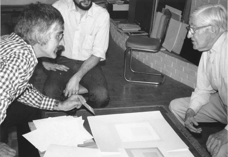 Black and white photograph of Tyler and Albers looking over a print