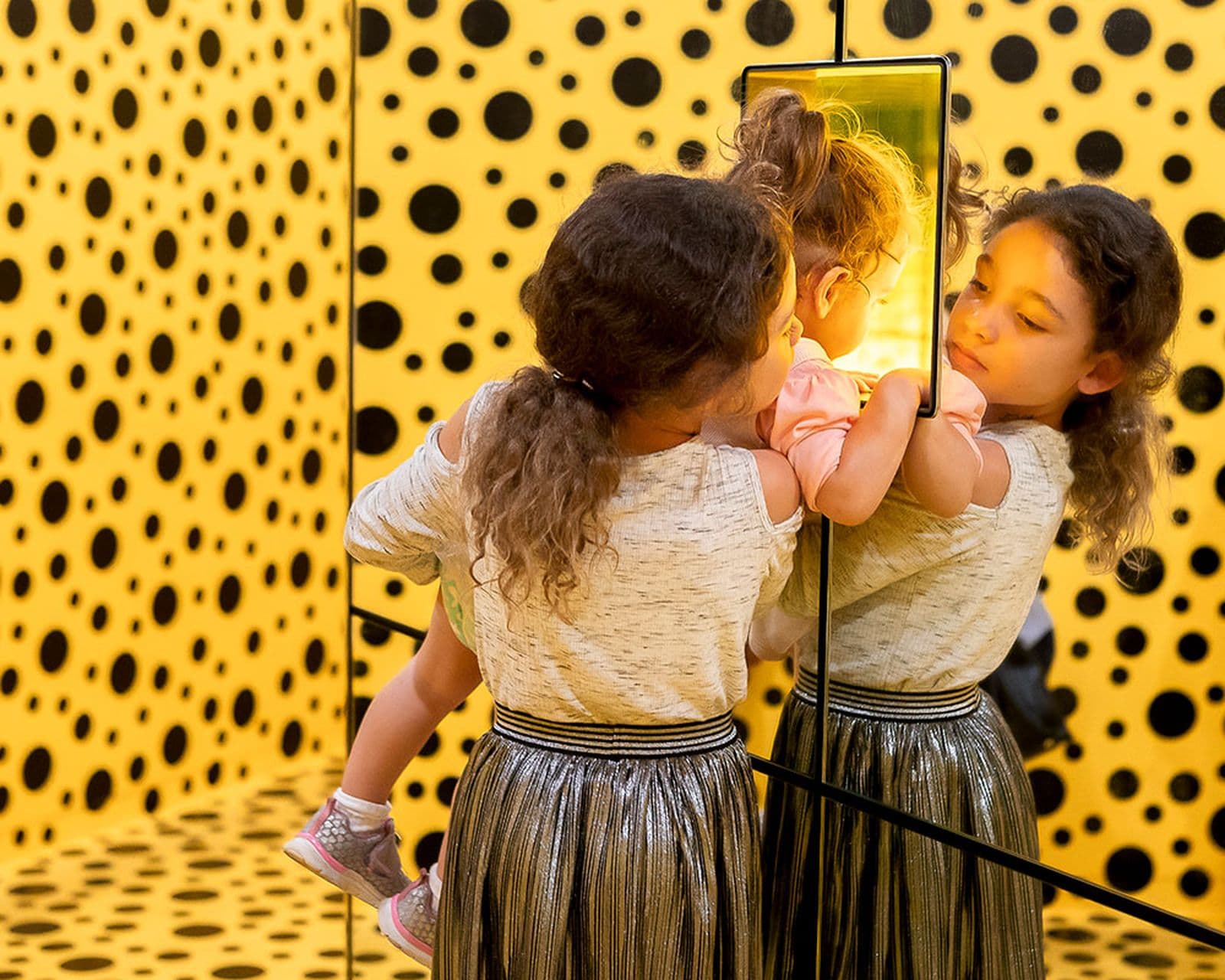 Two young visitors take a peek inside the camouflaged mirror box