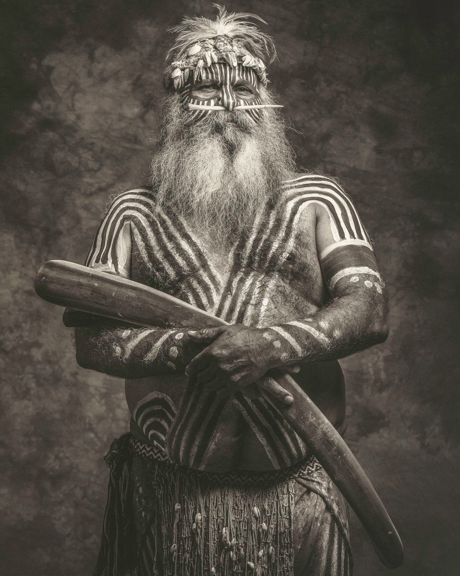 A black and white photograph of a man in body paint