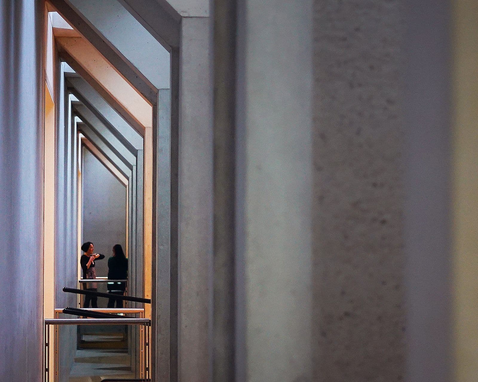 Photograph of building interior with concrete framing couple in distance