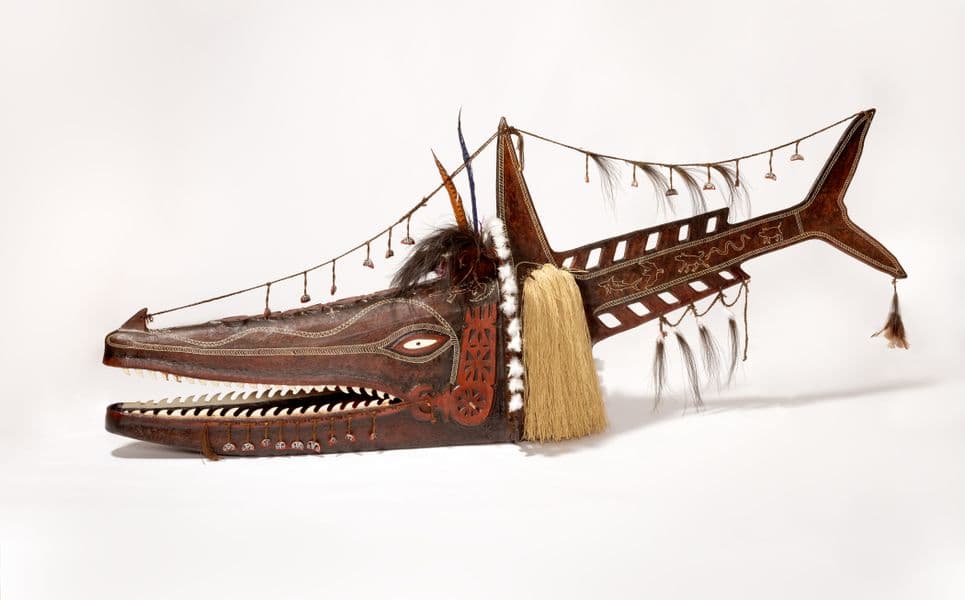 an intricately carved and decorated oversized mask in the shape of a shark
