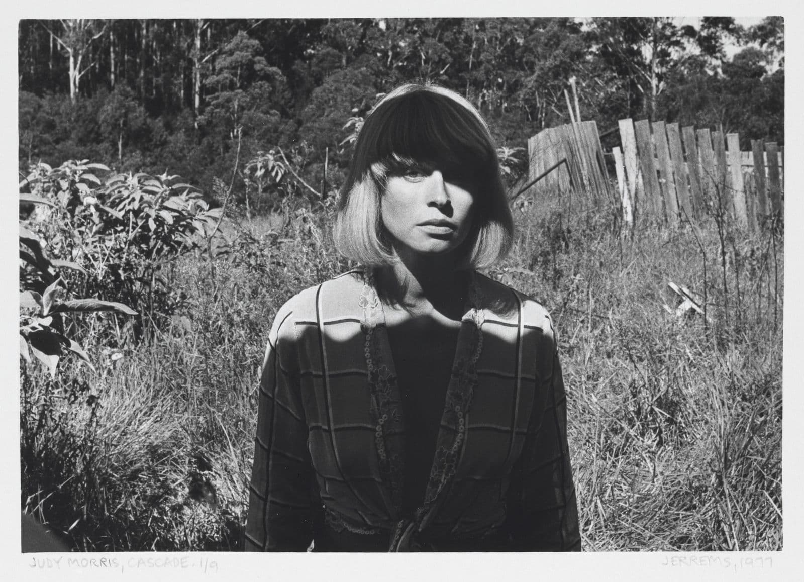 Black an white photograph of young woman with short blonde hair in front of bushland