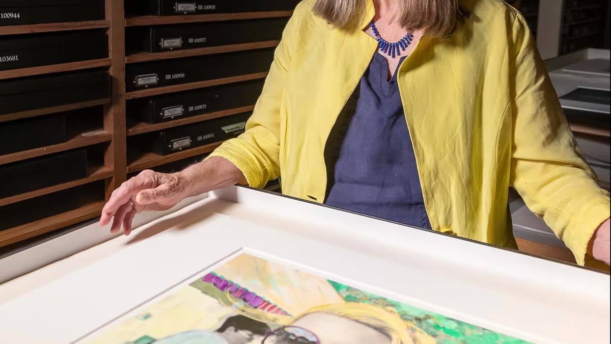 A video still of a woman standing above an artwork